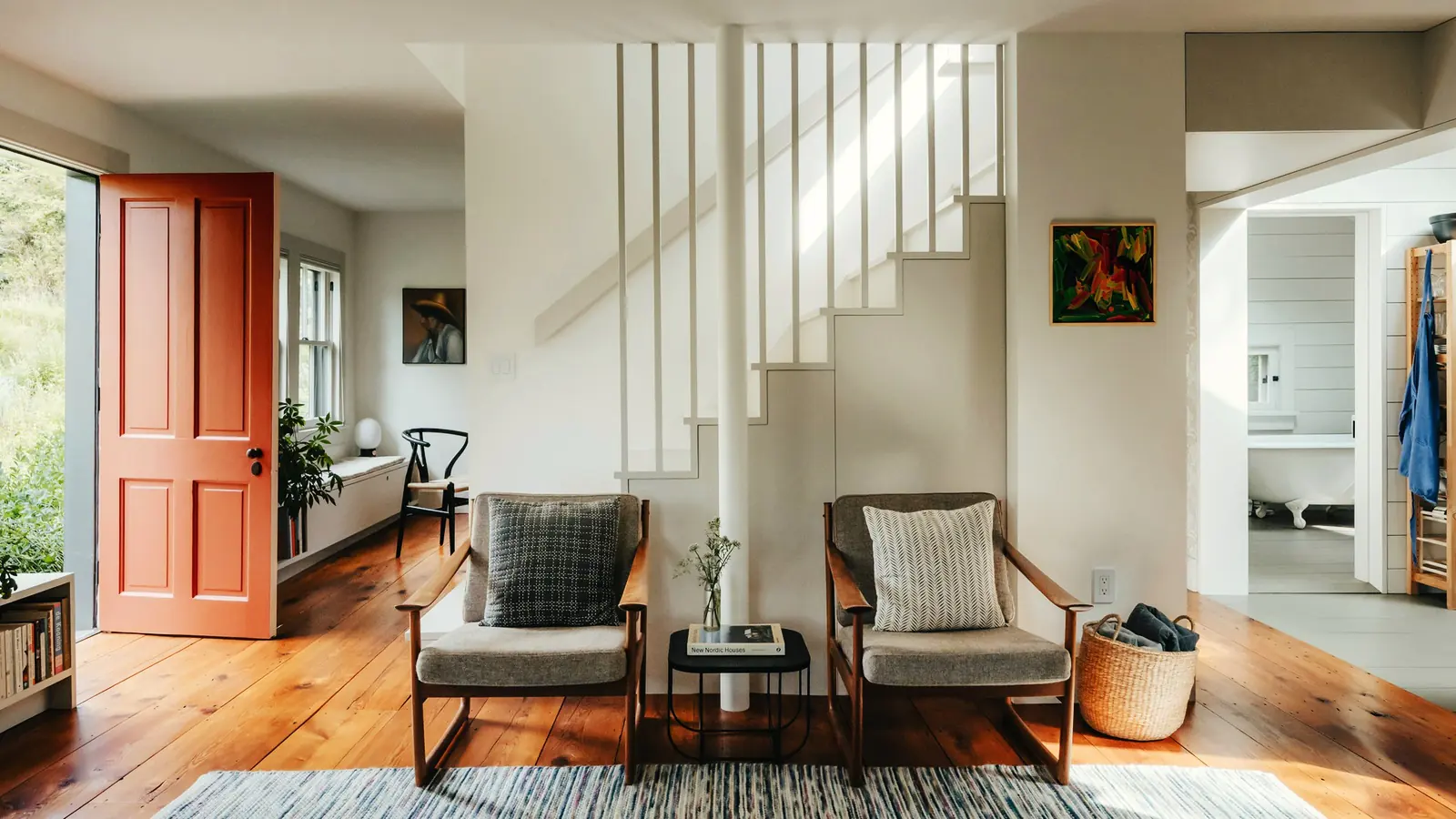 Lichte woonkamer met een witte trap en houten vloer
