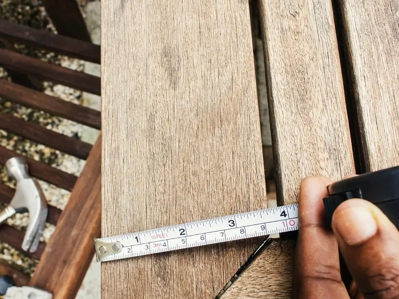 Een houten plank wordt opgemeten met een rolmaat
